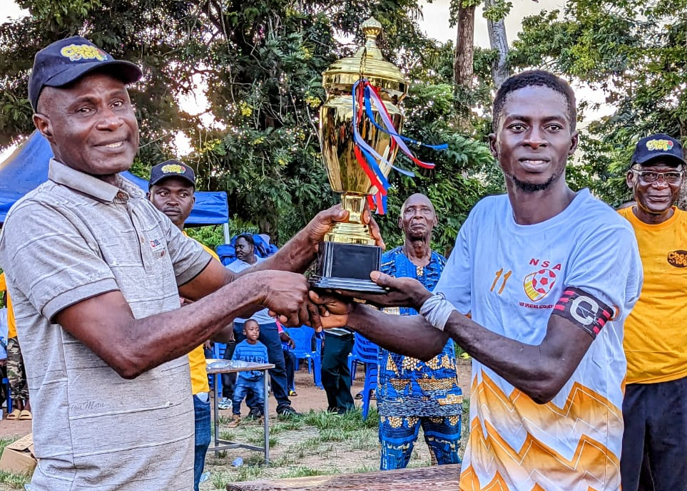 Remise du trophée de la coupe du DPFK au capitaine de NSA par le président du district. 